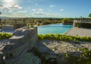 The infinity pool at the Mayan Baths hot springs near San Miguel de Allende, with a carved feathered-serpent sculpture and countryside views