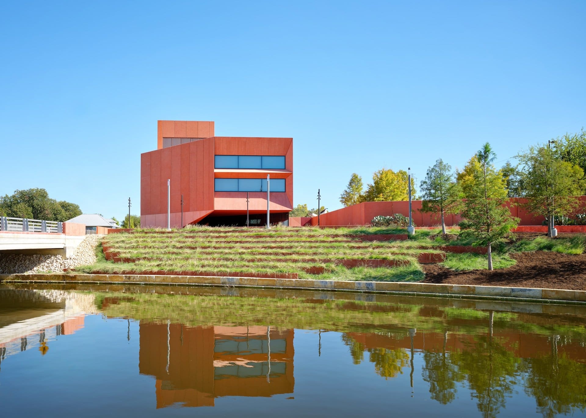 Ruby City contemporary art museum's crimson building reflected in water, San Antonio