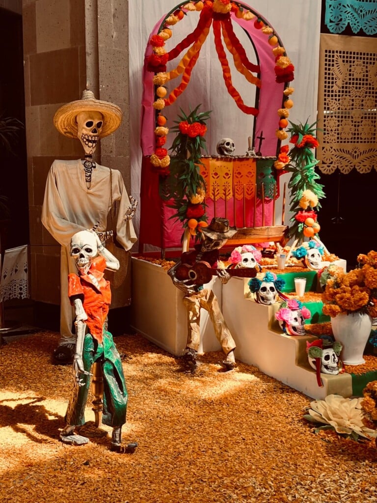 Día de los Muertos altar with skeleton figures, papel picado and marigold petals