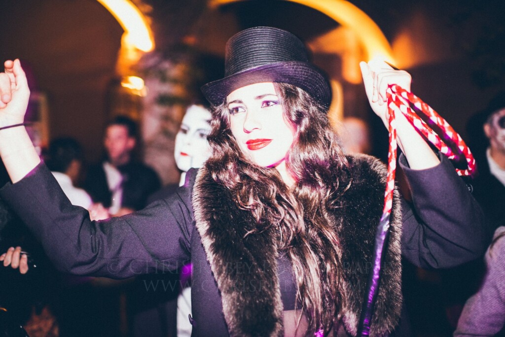 Woman in a top hat dancing at a Día de Muertos night celebration in San Miguel de Allende