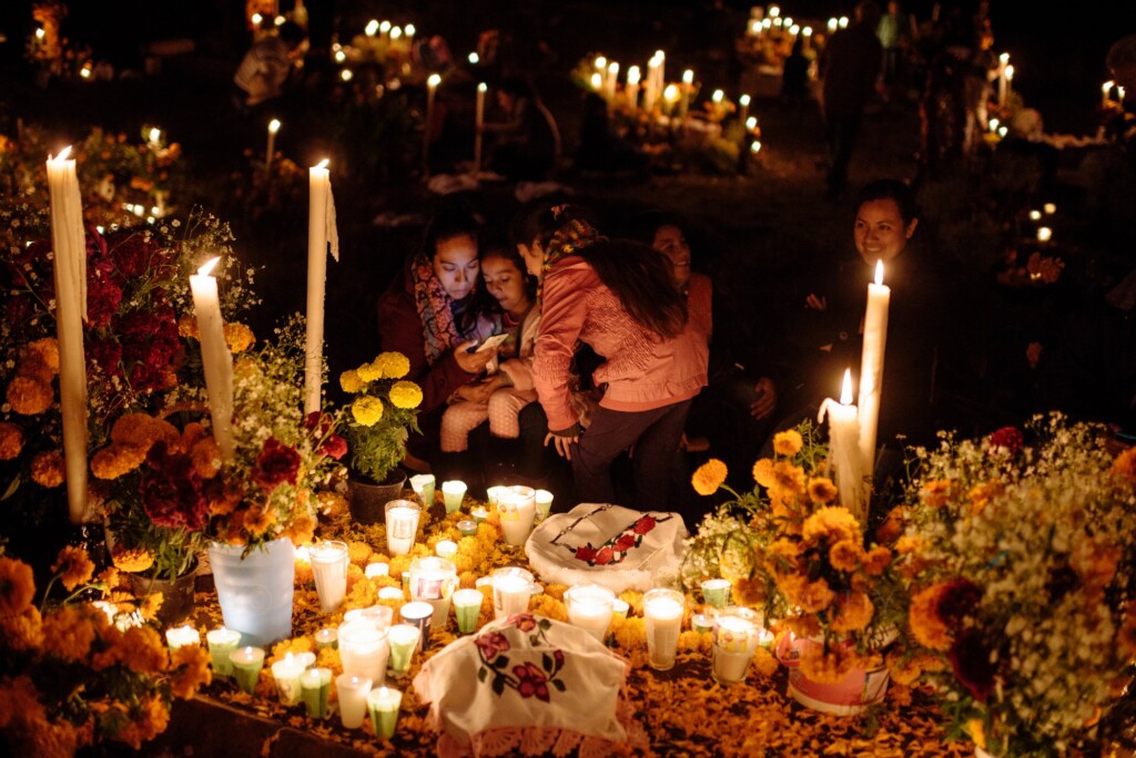 Families gathered with food and candles around marigold-covered graves on Noche de Muertos near Pátzcuaro