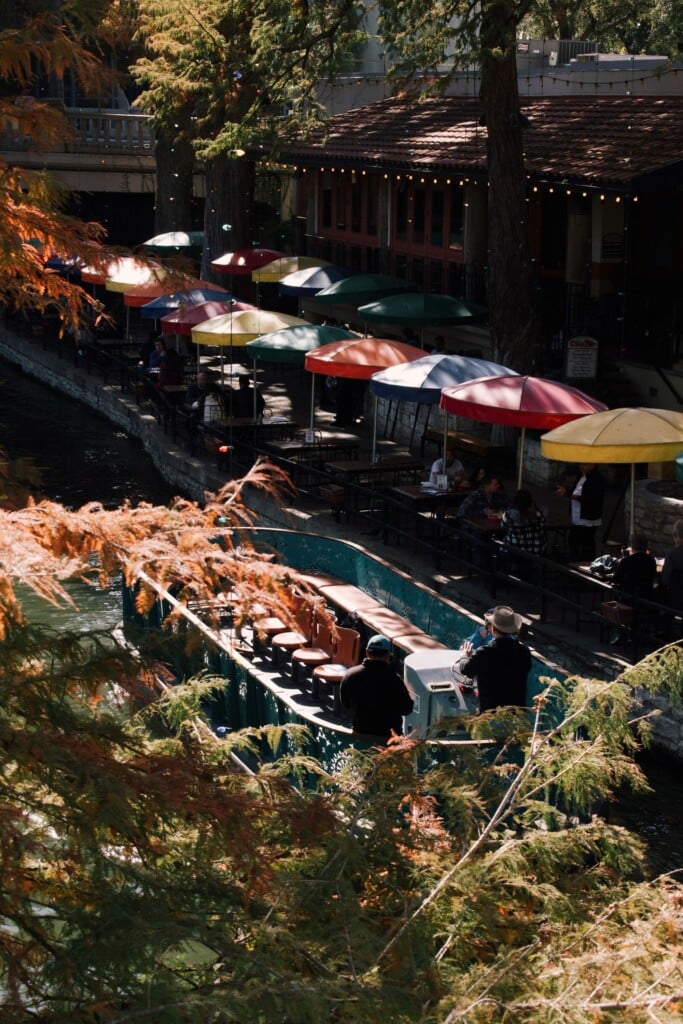 River barge passing colorful umbrellas on the San Antonio River Walk